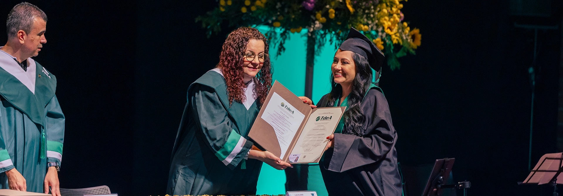 La decana de la Facultad de Derecho, Luz Elena Mira Olano, le entrega el diploma a una graduanda.