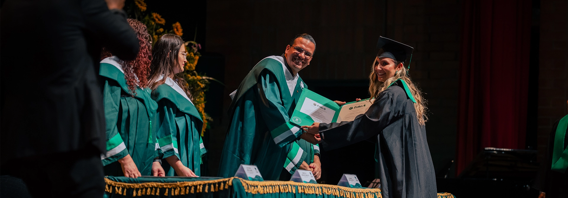 El rector del TdeA, Leonardo García Botero, le entrega diploma a una graduanda.