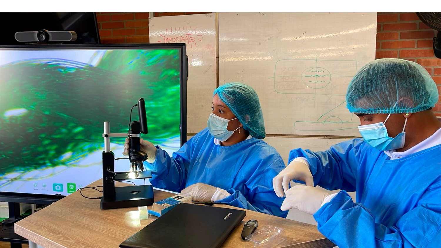 Dos estudiantes del TdeA analizan muestras en el microscopio.