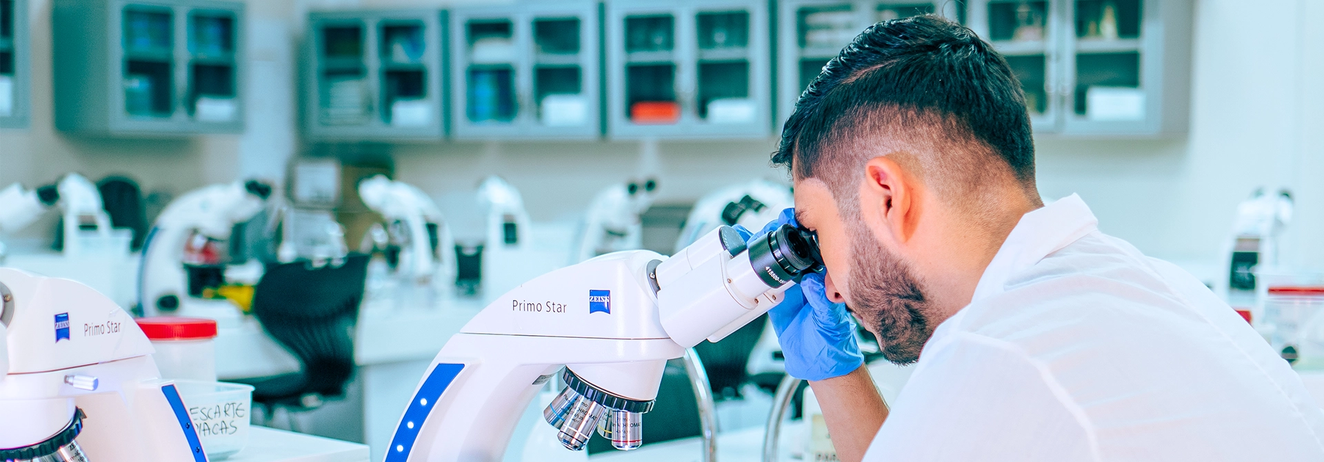 Estudiante observando un microscopio en el laboratorio de química.