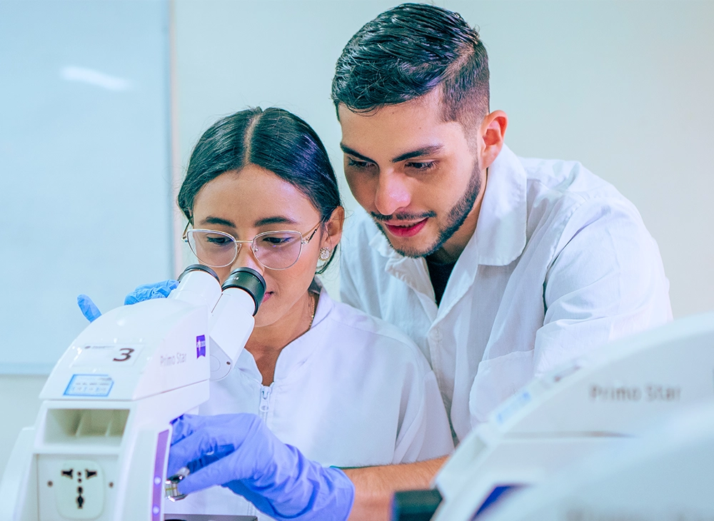 Dos estudiantes observando por el microscopio en el laboratorio de química.