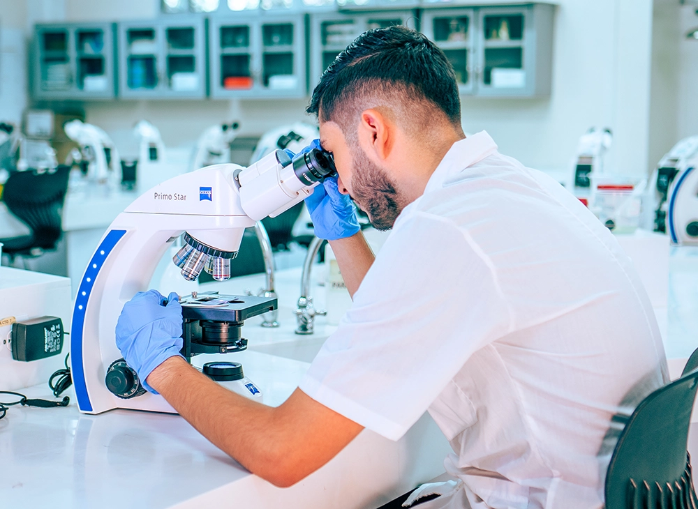 Estudiante observando un microscopio en el laboratorio de química.